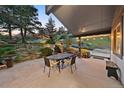 Beautiful outdoor patio with a water feature, dining table and chairs, surrounded by lush landscaping and mature trees at 812 Aspen Rd, Golden, CO 80401