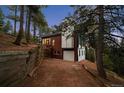 A beautiful home with an attached garage surrounded by tall trees, offering privacy and seclusion at 13910 Blue Jay Ln, Larkspur, CO 80118
