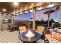 Relaxing covered deck with a fire table, comfortable seating, TV, dining table and barbecue grill at 5181 Appleton Way, Castle Rock, CO 80104