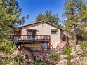 Exterior view of house featuring a balcony and stone foundation surrounded by trees at 5336 High Rd, Evergreen, CO 80439
