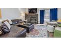 Living room featuring comfortable seating with a stone fireplace, colorful rug, and natural light at 12093 W Cross Dr # 304, Littleton, CO 80127