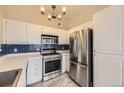 Well-lit kitchen featuring stainless steel appliances, white cabinetry and blue backsplash at 8358 Pebble Creek Way # 204, Highlands Ranch, CO 80126