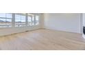 Bright and spacious living room featuring pristine white walls, light hardwood floors and large windows at 3856 Treadway Pt, Castle Rock, CO 80108
