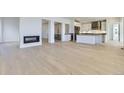 Open concept living room with modern fireplace and hardwood floors leading to the kitchen at 3856 Treadway Pt, Castle Rock, CO 80108