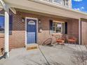 Charming front porch features brick facade and a blue front door with seating at 6720 S Adams Way, Centennial, CO 80122