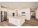Bright and airy kitchen with a large center island, stainless steel appliances, and wood-look flooring at 631 Sunrise St, Erie, CO 80516