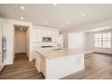 Bright kitchen with a large center island, stainless steel appliances, recessed lighting, and wood-look floors at 631 Sunrise St, Erie, CO 80516