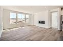 Modern living room with wood-look floors, a linear fireplace, and large windows with plenty of natural light at 631 Sunrise St, Erie, CO 80516