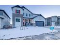 Two-story home with gray siding, red accents, and a snowy front yard at 8512 Orchard City Dr, Littleton, CO 80125