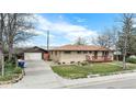 A single story home featuring a brick facade, mature trees, a detached garage and long driveway at 4395 E Arapahoe Pl, Centennial, CO 80122