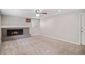 Spacious living room featuring a cozy fireplace, neutral carpet, and modern ceiling fan at 1962 S Ivory Way, Aurora, CO 80013