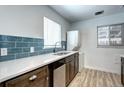 Well-lit kitchen with stainless steel appliances, stylish blue tile backsplash, and in-unit washer/dryer at 361 N Raleigh St, Denver, CO 80219