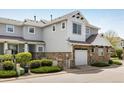 Beautiful townhome displaying stone accents, a garage, a well-maintained landscape, and neutral gray siding at 14000 Winding River Ct # T3, Broomfield, CO 80023