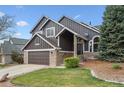 Lovely two-story home showcasing a green lawn, stone detailing, an attached garage, and charming architectural features at 9714 Chanteclair Cir, Highlands Ranch, CO 80126
