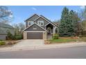 Inviting two-story home with a well-maintained lawn, stone accents, and an attached garage, set against a clear blue sky at 9714 Chanteclair Cir, Highlands Ranch, CO 80126
