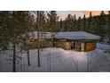 Stone facade home with snow-covered roof, surrounded by tall evergreen trees, evoking a winter wonderland at 2383 Tiger Rd, Breckenridge, CO 80424