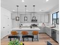 A kitchen with an island with bar seating and modern pendant lighting above, set against a neutral color palette at 2078 S Holly St # 3, Denver, CO 80222