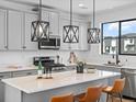 Stylish kitchen boasts gray cabinets, quartz countertops, stainless appliances, and modern pendant lighting at 2078 S Holly St # 3, Denver, CO 80222