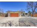Ranch-style home with an orange garage door and a rock-covered front yard at 2826 S Lamar St, Denver, CO 80227