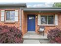 Close-up of front porch featuring a brick facade, blue door, and a decorative chair at 3285 S Delaware St, Englewood, CO 80110