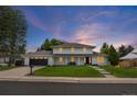 Beautiful home exterior highlighted by a lush lawn and a dark-colored garage door, set against a vibrant twilight sky at 5853 S Havana Ct, Englewood, CO 80111