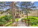 Lovely exterior view of the multi-level home featuring mature trees and a charming walkway at 9995 E Harvard Ave # 290, Denver, CO 80231