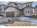 Two-story home showcasing a two-car garage, stone accents, and a well-maintained front yard at 1660 Candleflower Dr, Castle Pines, CO 80108