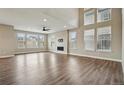 Bright living room with large windows, high ceilings, modern ceiling fan, fireplace and wood floors at 1660 Candleflower Dr, Castle Pines, CO 80108