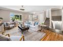 Bright living room featuring hardwood floors, a large window, a comfortable sofa, and a view of the staircase at 8712 W 64Th Way, Arvada, CO 80004