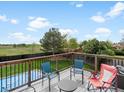 Outdoor deck with black metal railing, chairs, a table, and a view of the grass yard and trees at 10536 Garrison St, Westminster, CO 80021
