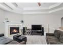 Cozy living room with a fireplace, tray ceiling, and plush gray carpeting at 2558 Northview Pl, Castle Rock, CO 80104