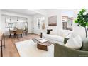 Bright living room with white sofa, art, wood floors, and dining room view at 333 Quitman St, Denver, CO 80219