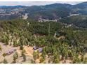 A stunning aerial view showcasing the cabin nestled among the towering pines, with mountains in the background at 54 Zaza Ln, Evergreen, CO 80439