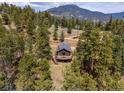 An aerial view of a cozy mountain cabin with a deck surrounded by lush trees at 54 Zaza Ln, Evergreen, CO 80439