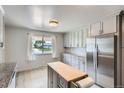 Bright kitchen with an island, stainless steel refrigerator, light grey cabinets, and a view from the window at 1785 S Zuni St, Denver, CO 80223