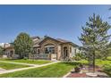 Beautiful home featuring a stone facade, landscaped lawn, and a cozy front porch for relaxing and enjoying the outdoors at 2700 W Greens Pl, Littleton, CO 80123