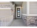 Close-up of the front door showcasing stone accents and a modern glass insert design that exudes curb appeal at 12846 Palisade St, Mead, CO 80504