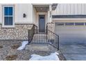 Close-up of the entrance to a two-story home, featuring stone accents, stairs with railing, and a gray front door at 8926 S Rome Ct, Aurora, CO 80016