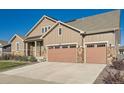 Beautiful home exterior showcases a well-maintained lawn, stone details, and an attached garage at 8778 S Quatar St, Aurora, CO 80016