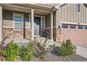 Inviting front entrance with stone accents, manicured landscaping, and a covered porch at 8778 S Quatar St, Aurora, CO 80016