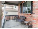 Cozy front porch with wicker furniture and brick siding, perfect for relaxing outdoors at 6488 S Kewaunee Way, Aurora, CO 80016