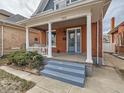 Inviting front porch with swing, supported by classic white columns and blue stairs at 3833 Umatilla St, Denver, CO 80211