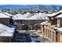 Street view of snow-covered townhomes with attached garages, in a well-maintained community on a sunny day at 8571 Gold Peak Dr # C, Highlands Ranch, CO 80130