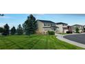 Well-maintained two-story home showcases a green lawn with patterned mowing and established trees at 16893 Trail View Cir, Parker, CO 80134