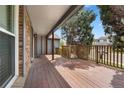 Spacious outdoor porch with stained wood floors, gray ceiling, brick details and railings at 15909 E Ford Pl, Aurora, CO 80017