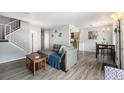 Bright open-concept living room with gray sofa, wood floors, and stairs at 2016 W 101St Ave, Thornton, CO 80260