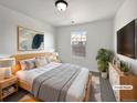 Bright bedroom featuring natural wood bed frame, light gray walls, modern art, and large window at 12713 Leyden St # E, Thornton, CO 80602