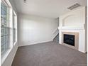 Carpeted living room features a fireplace, large window and adjacent staircase at 12713 Leyden St # E, Thornton, CO 80602