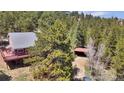 Wood home featuring a red deck, surrounded by lush green trees and a detached garage at 32187 Sylvan Rd, Golden, CO 80403