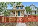 Charming two-story home with a welcoming front porch and a red picket fence and spring blossoms at 2538 Central Park Boulevard, Denver, CO 80238